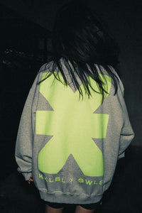 Frau im grauen Sweater mit neongelbe KKLBLxGWLS Logo und Print, Rückansicht aus GWLS x KKLBL