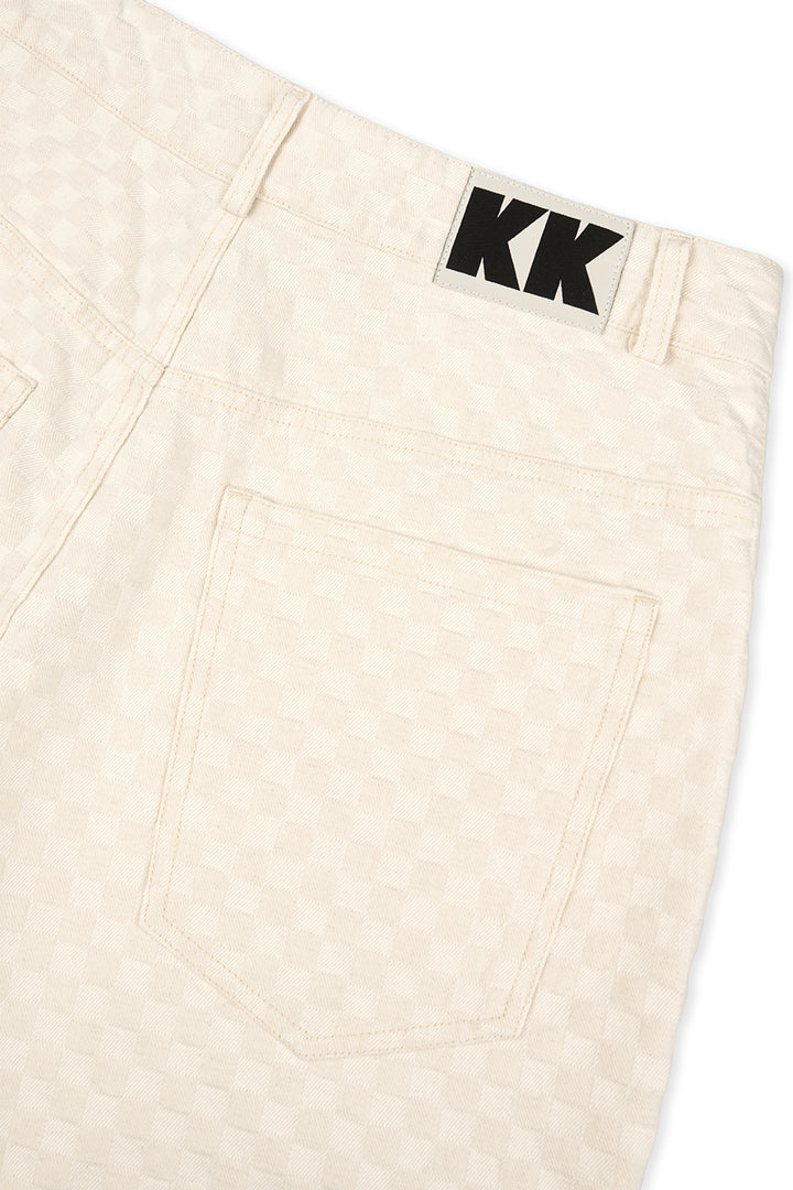 Detailaufnahme: Beige gemusterte Shorts mit schwarzem KK Logo-Patch aus The Tour 25 Collection