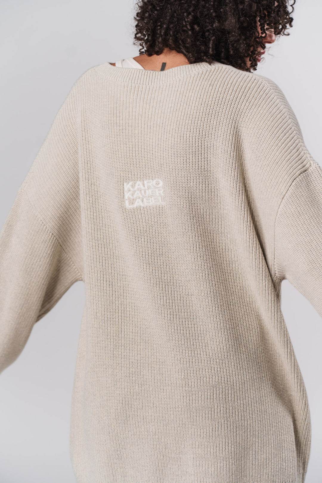 Frau im beigen Knit Sweater Sand, Rückansicht aus Out of the Blue Collection