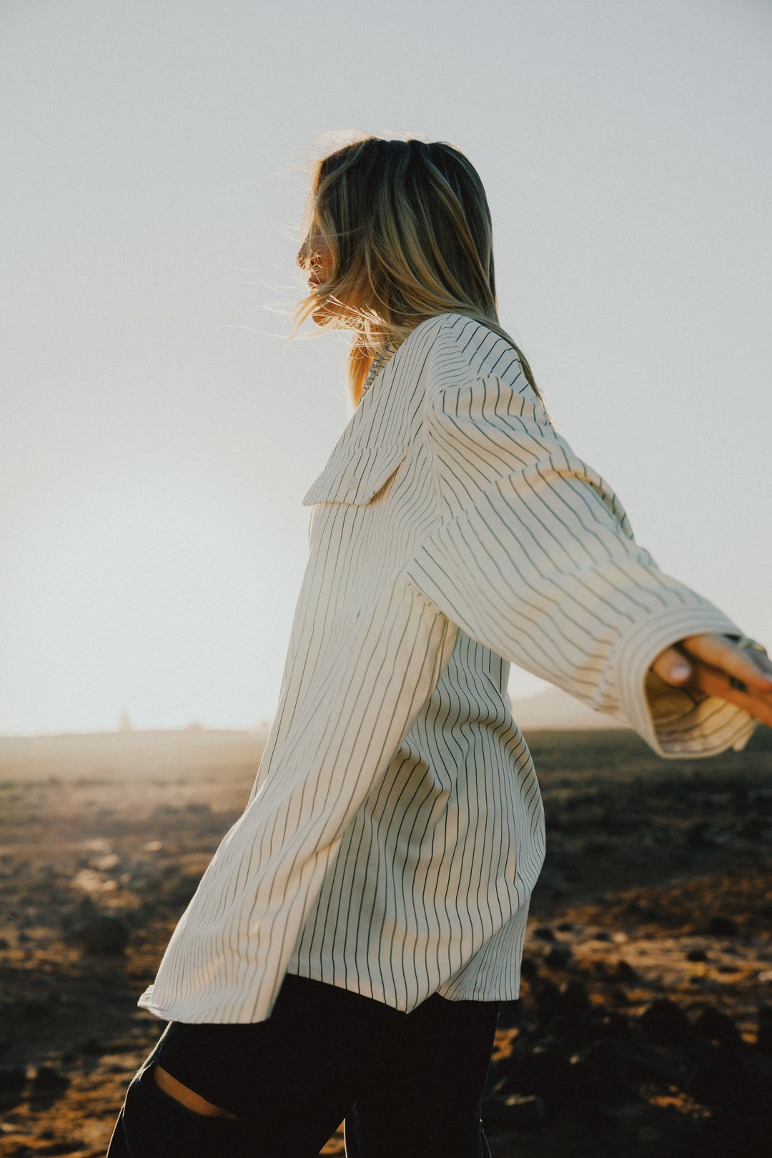 Frau in beige-schwarz gestreifter Oversized Bluse, seitliche Pose aus UNFILTERED