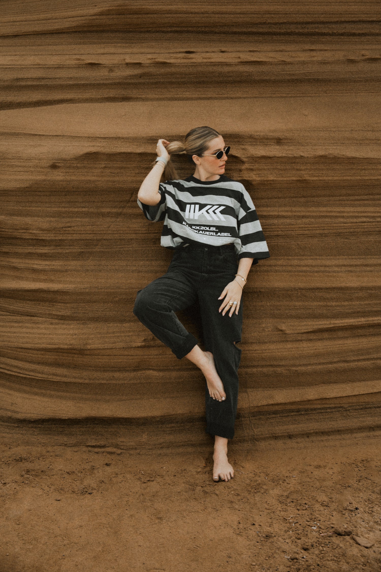 Ganzkörper: Frau im schwarz-grauen Streifen-T-Shirt mit KK Logo, aus UNFILTERED Collection