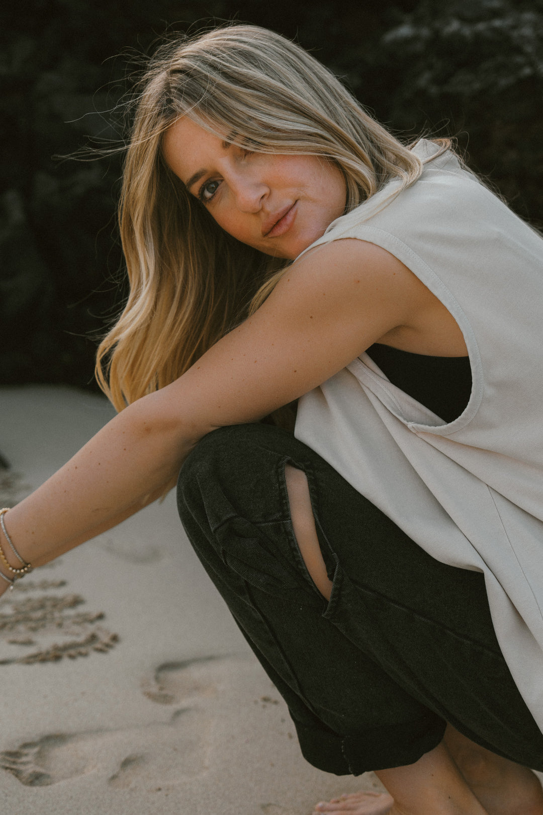 Frau im beigen Oversized Tanktop, seitlich sitzende Pose aus UNFILTERED Collection