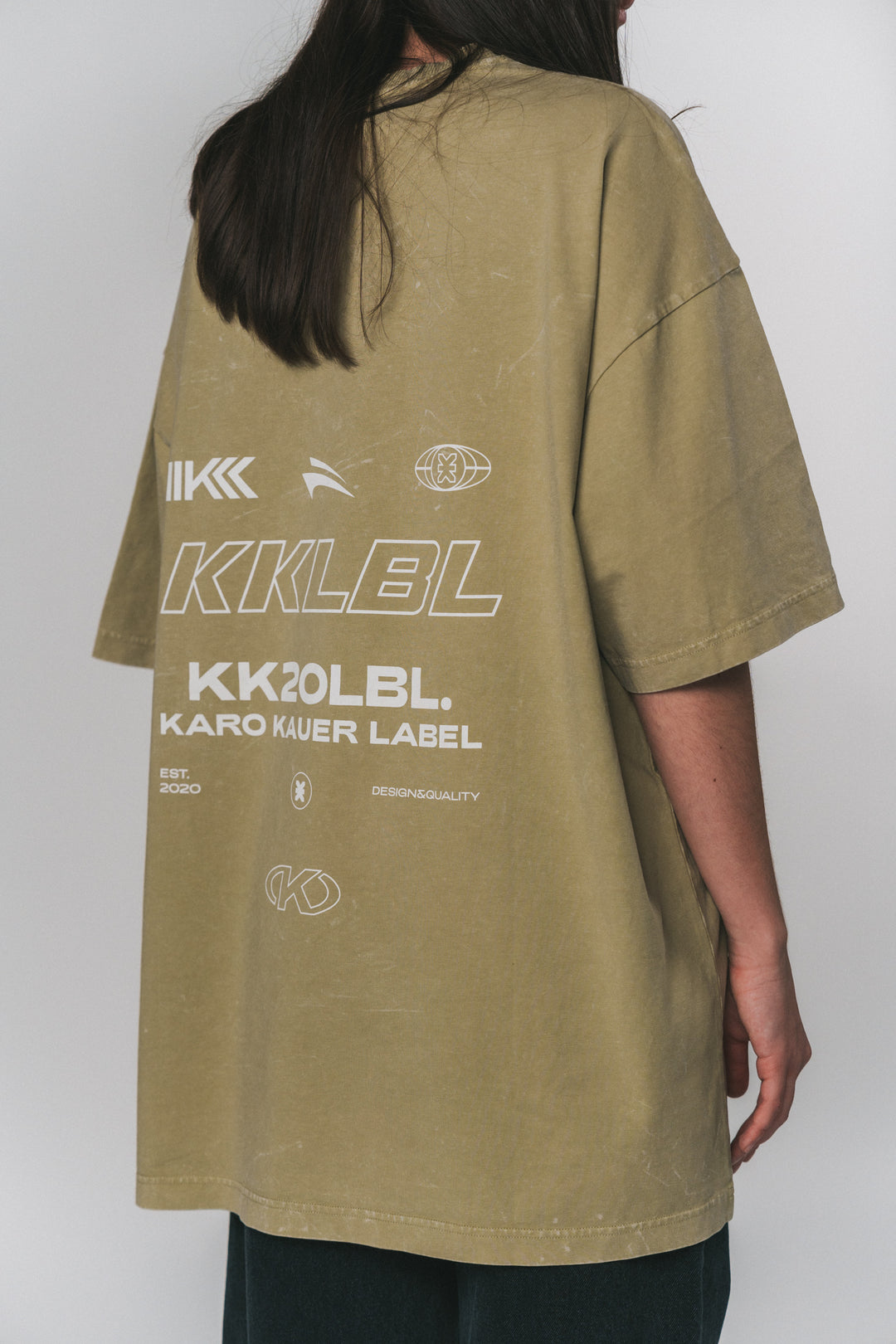 Frau im weißen T-Shirt KK20LBL mit schwarzem Print aus UNFILTERED, seitliche Rückansicht