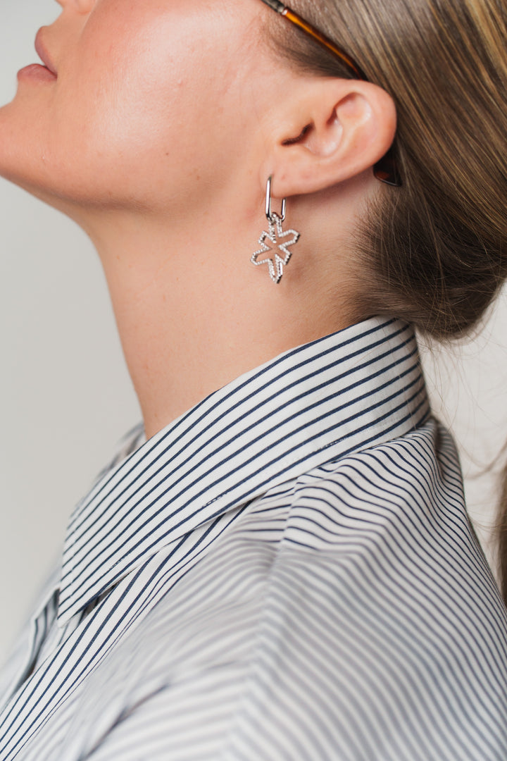 Eine Frau trägt silberne Oval Hoops Ohrringe aus The Escape Collection 