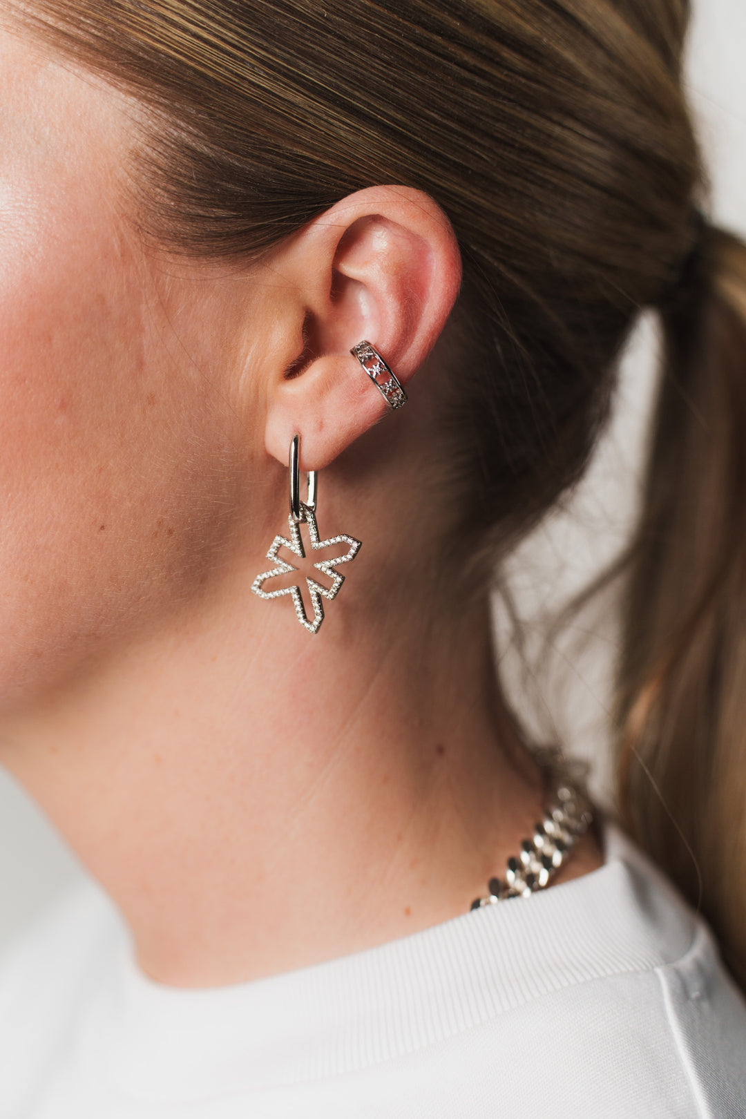 Frau im weißen Oberteil trägt silberne Earcuff und Oval Hoops Ohrringe