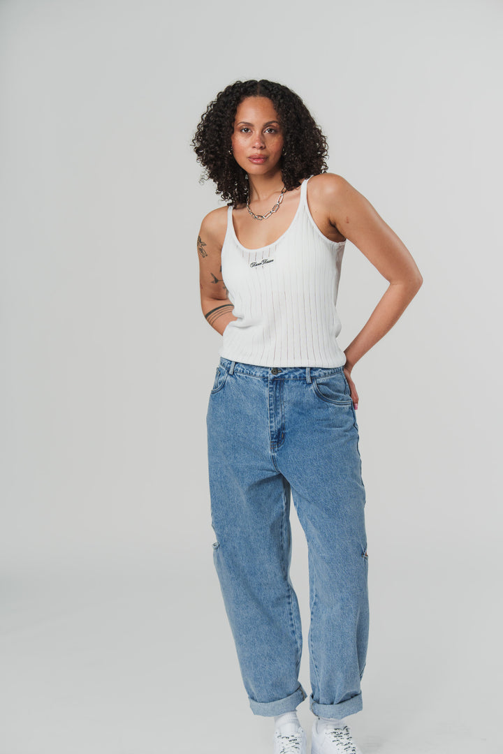 Ganzkörperaufnahme: Frontalansicht einer Frau im weißen Knit Top aus The Escape Collection