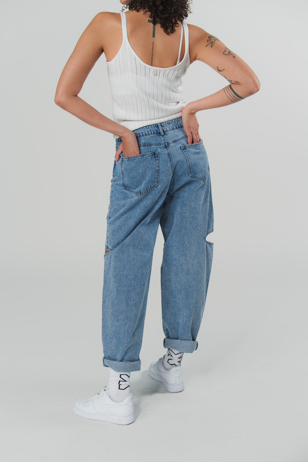 Ganzkörperaufnahme: Rückenansicht einer Frau in blauen Denim Pants mit Cut Out aus der Escape Collection