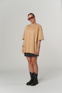 Seitliche Frontalansicht einer Frau im beigen T-Shirt Caramel aus The Escape Collection