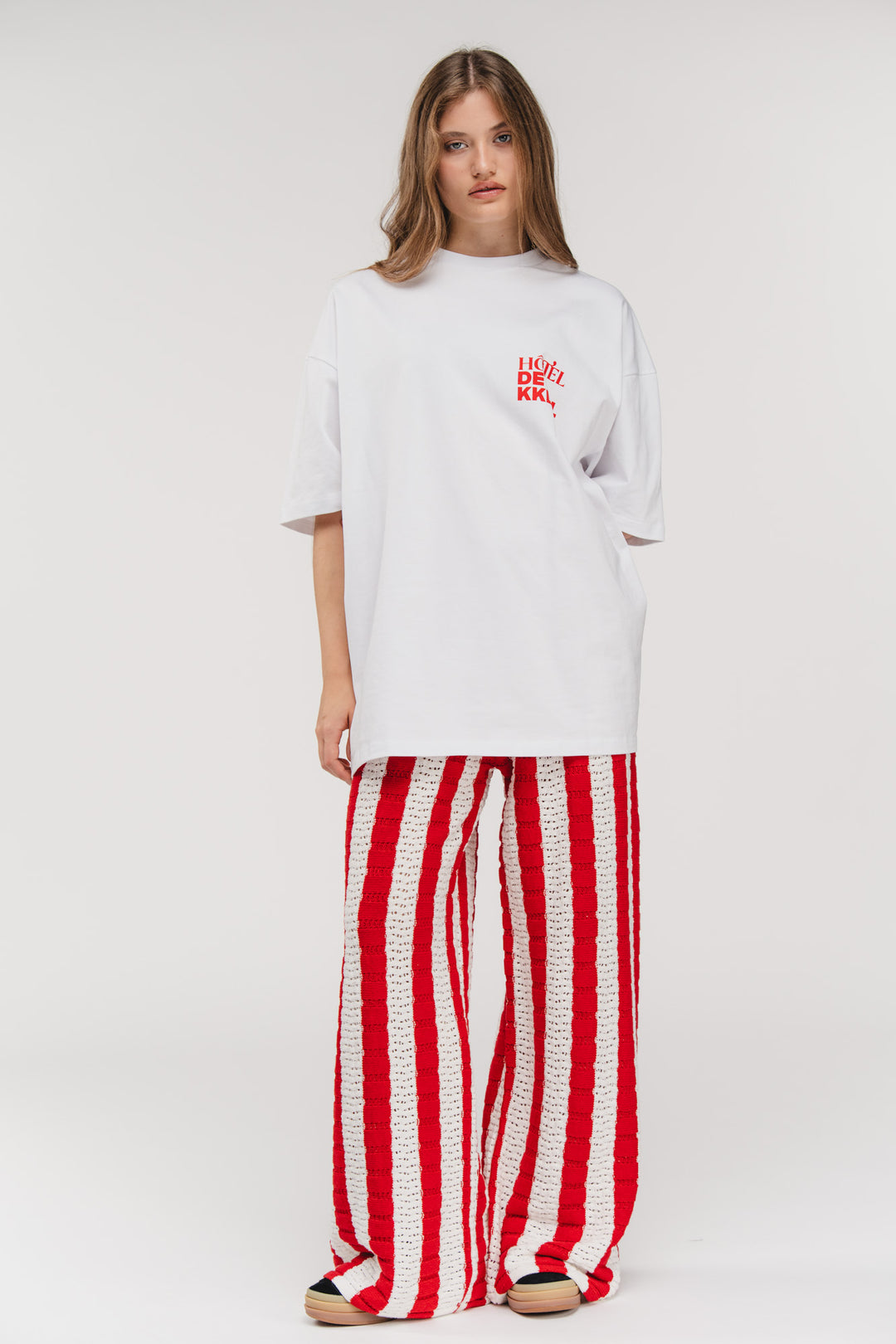 Ganzkörper-Model-Shot, Knit Pants Striped Red gestylt mit weißem Oversized-Shirt, frontale Pose
