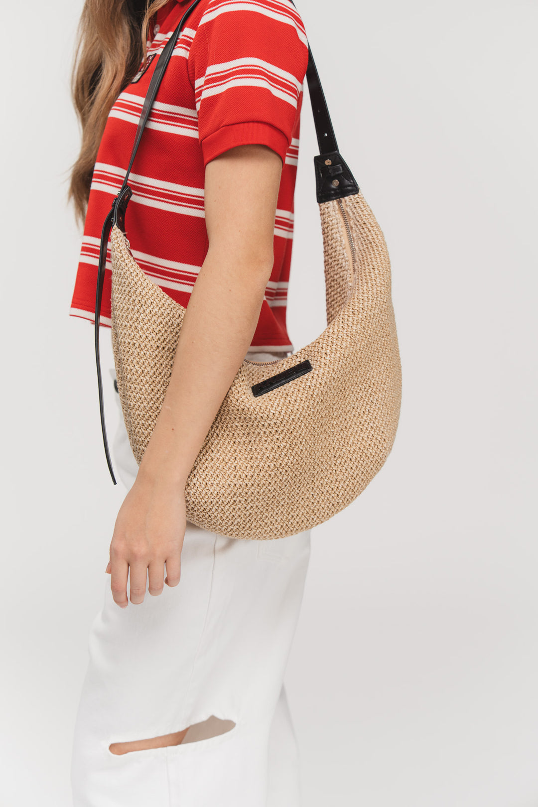 Moon Bag Crochet, Halbkörper frontal, Halbmond-Bag aus Bast, schwarzer Tragegurt, lässig am Körper