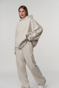 Ganzkörperaufnahme: Frontalansicht einer Frau im beigen Basic Hoodie aus der Evergreen Collection