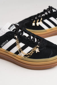 Accessory Chain Gold, Detailaufnahme doppellagige Goldkette mit KKLBL-Logoanhänger mit Glitzersteinen am Sneaker