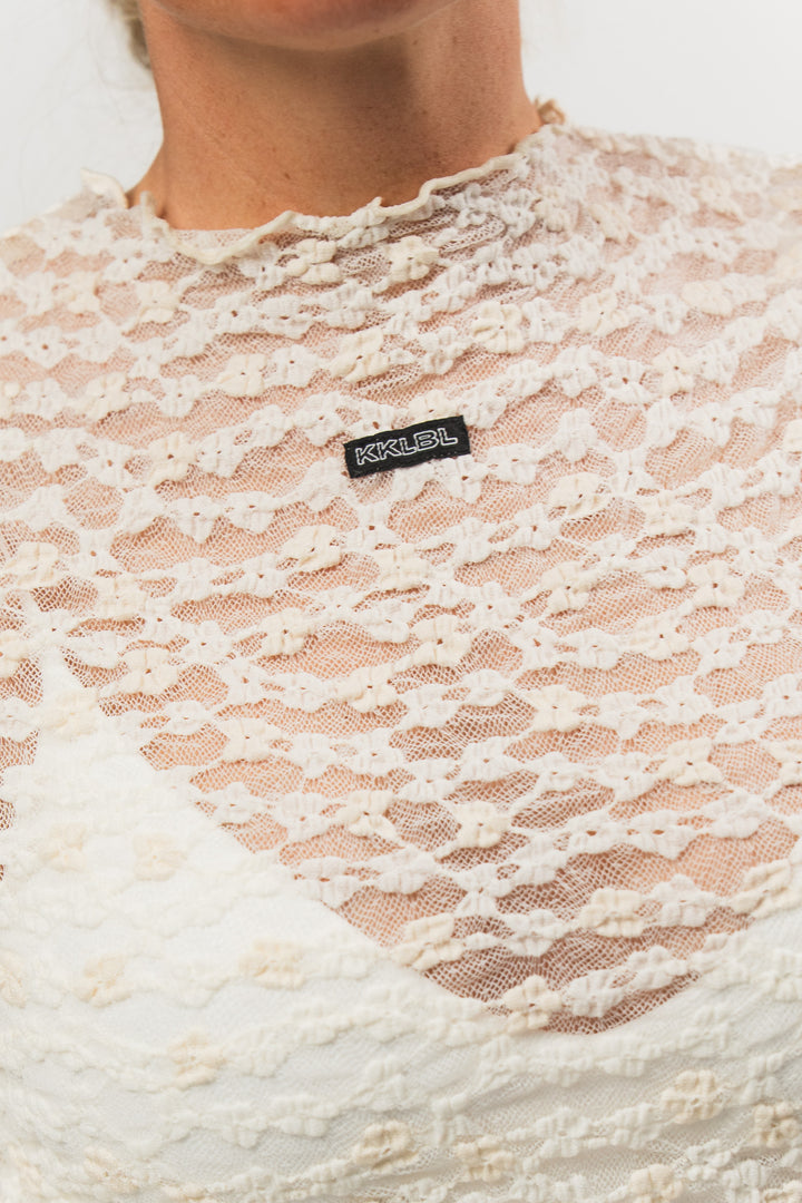 Lace Longsleeve Offwhite, Detailaufnahme Spitzenblumen-Textur und Weblabel, offwhite Spitzenstoff transparent