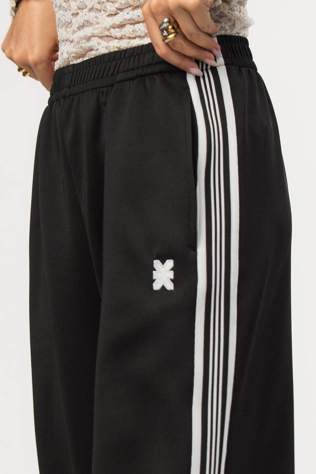 Retro Pants Black, Detailaufnahme Bund mit eingesticktem Logo und weißem Seitenstreifen, schwarzer Stoff