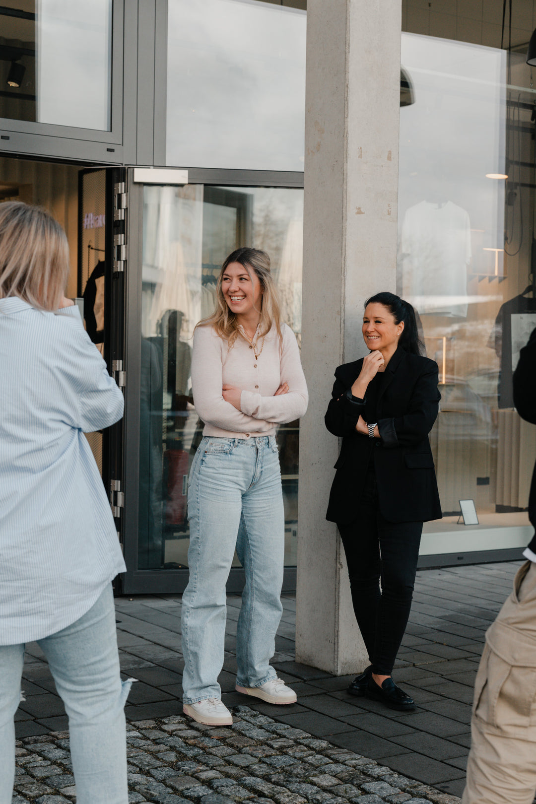 Gruppenaufnahme: Frauen in hellen und schwarzen Oberteilen vor Store,