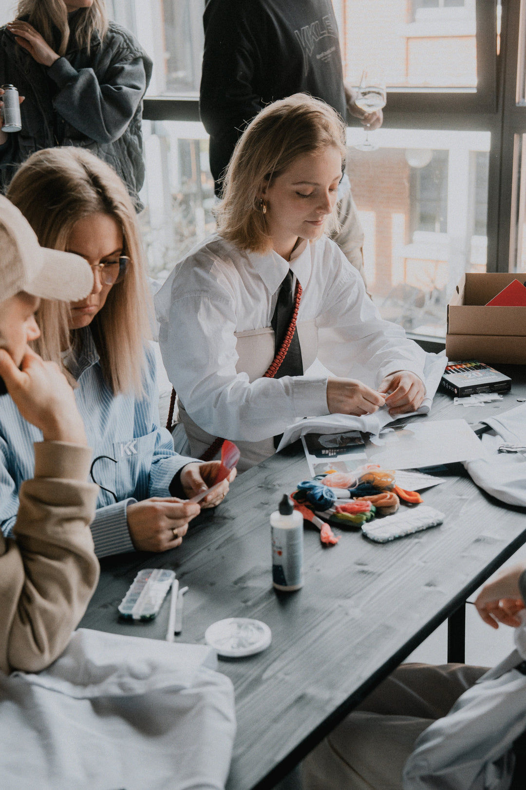 Gruppenaufnahme: Frauen in hellen Oberteilen bei kreativer Arbeit, sitzende Pose am Tisch
