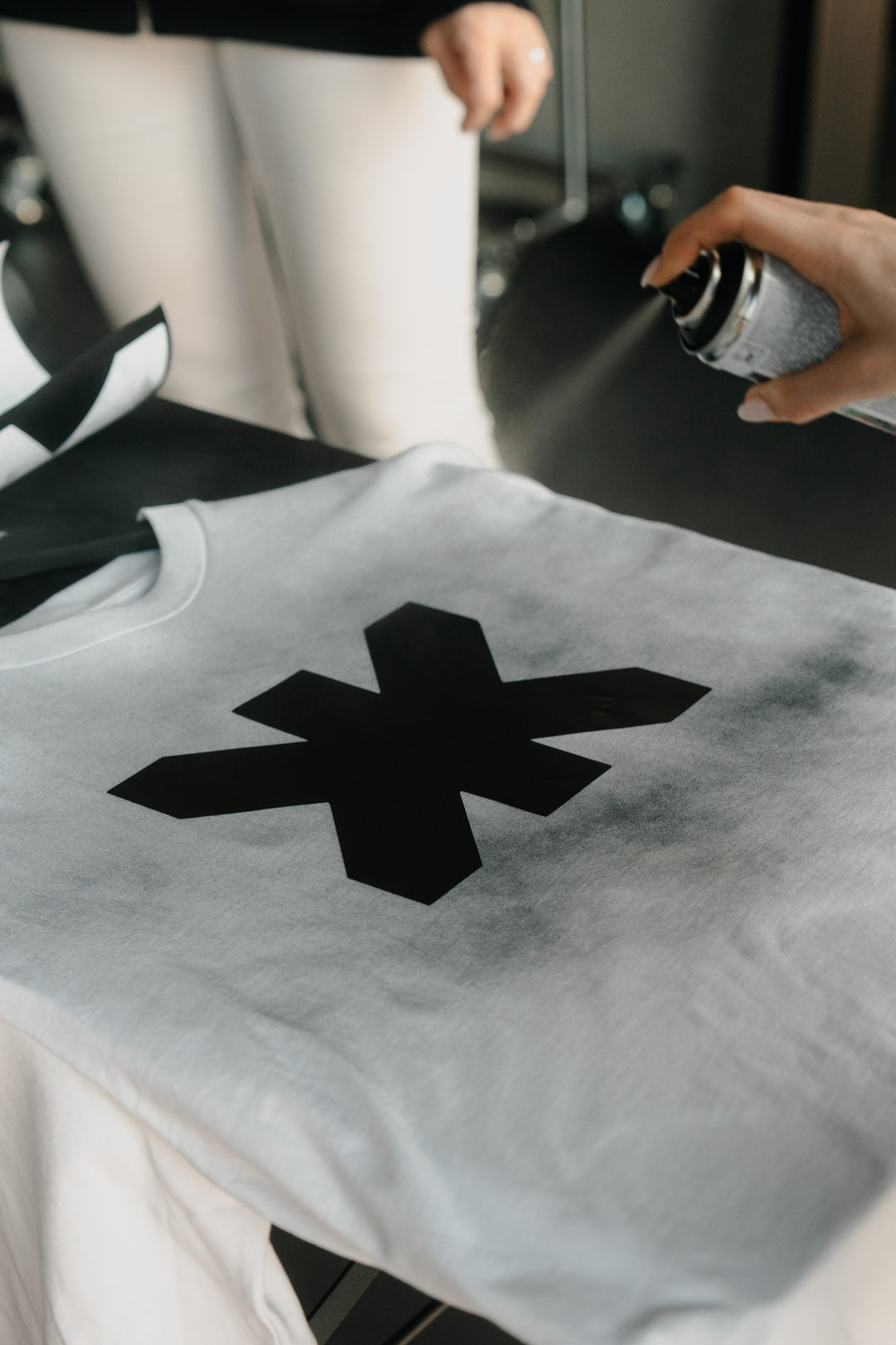 Detailaufnahme: Weißes T-Shirt mit schwarzem KK-Print wird bearbeitet