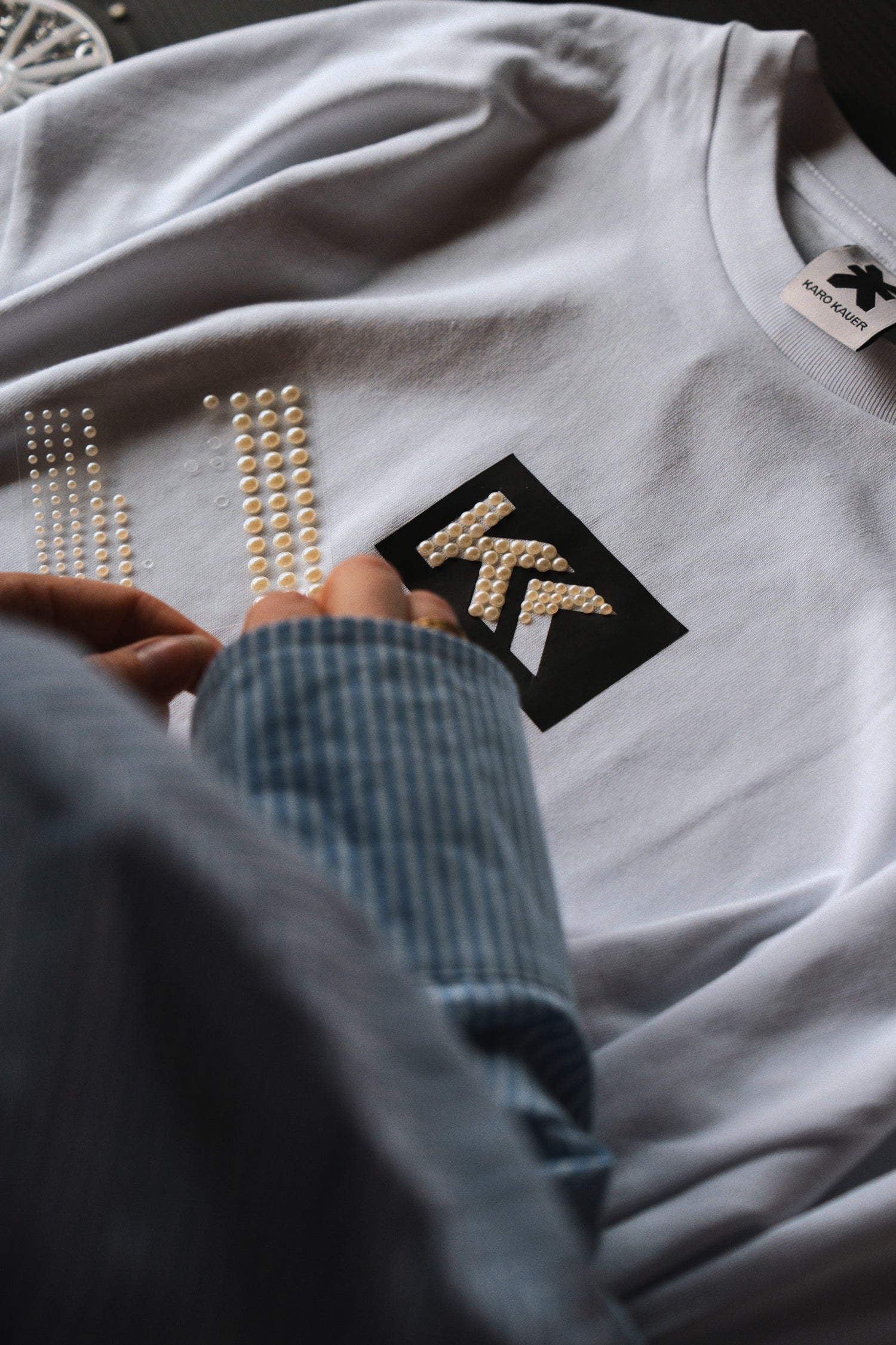 Detailaufnahme: Weißes T-Shirt mit Perlen-KK Design wird personalisiert