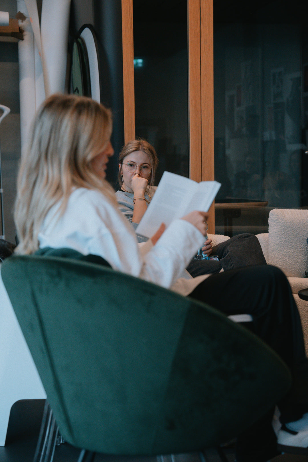 Frauen in hellen Oberteilen beim Lesen, sitzende Pose