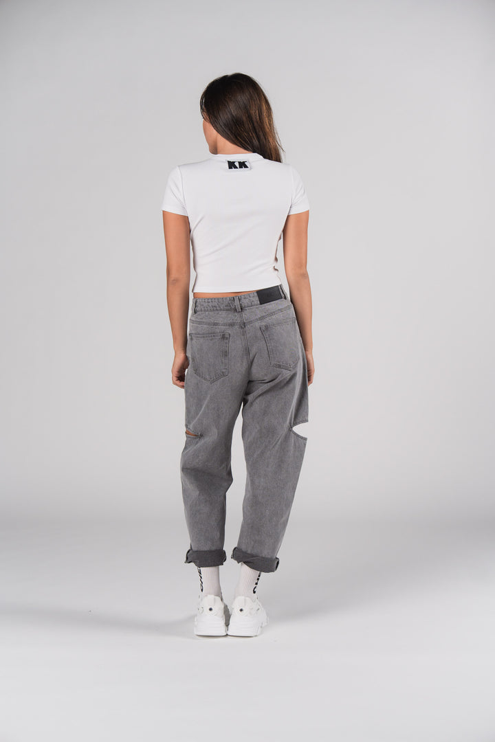 Rückansicht: Frau in weißem T-Shirt mit KK Print und grauen Denim Pants Grey Cut Out Petite