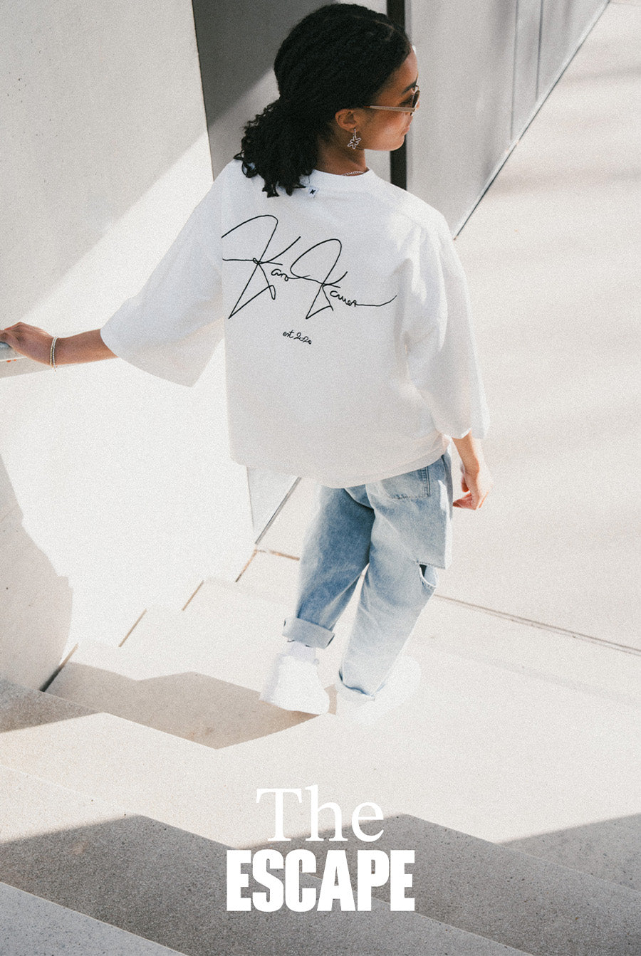 Ganzkörperaufnahme: Rückenansicht einer Frau im weißen Cropped T-Shirt aus The Escape Collection