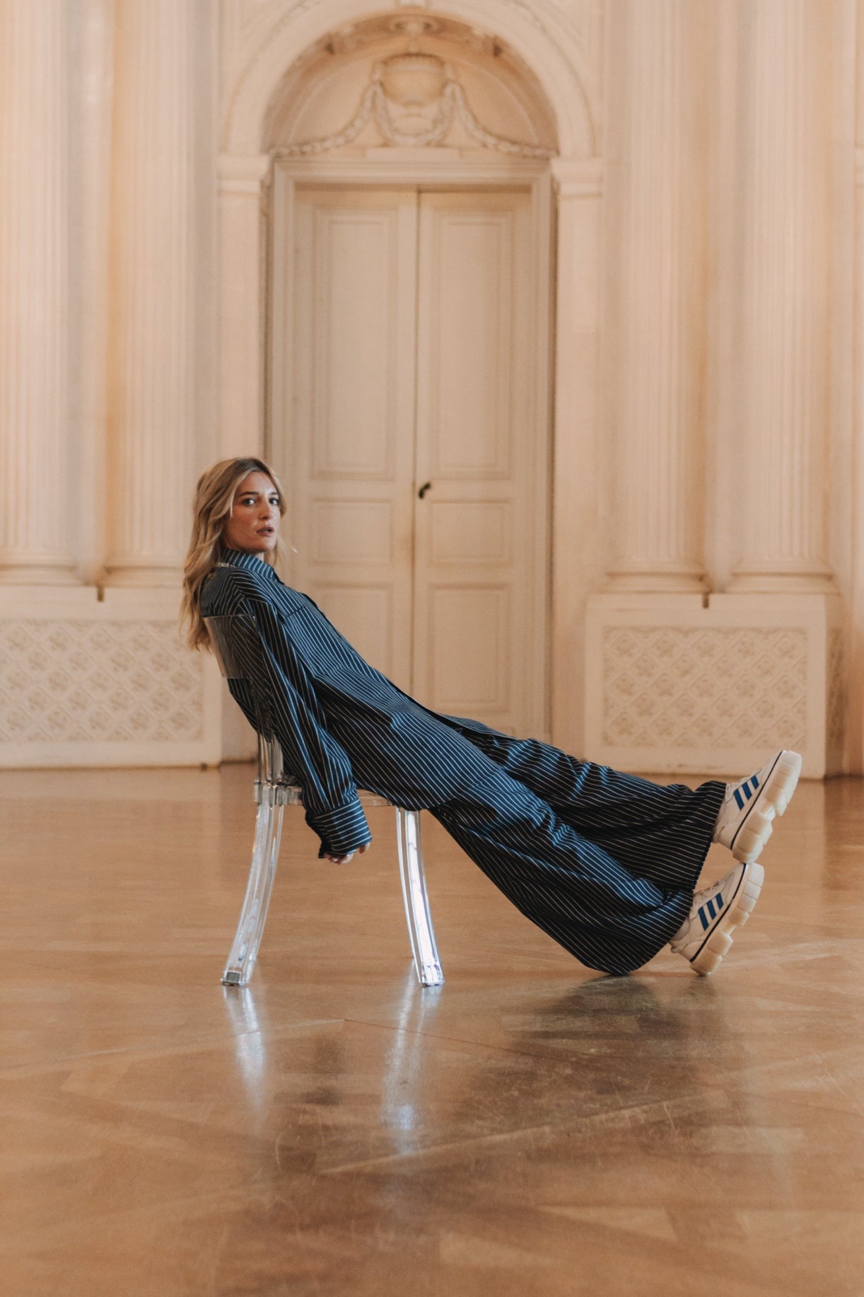 Ganzkörper: Frau in blau-schwarzer Woven Blouse Striped mit Rollkragen, sitzende Pose