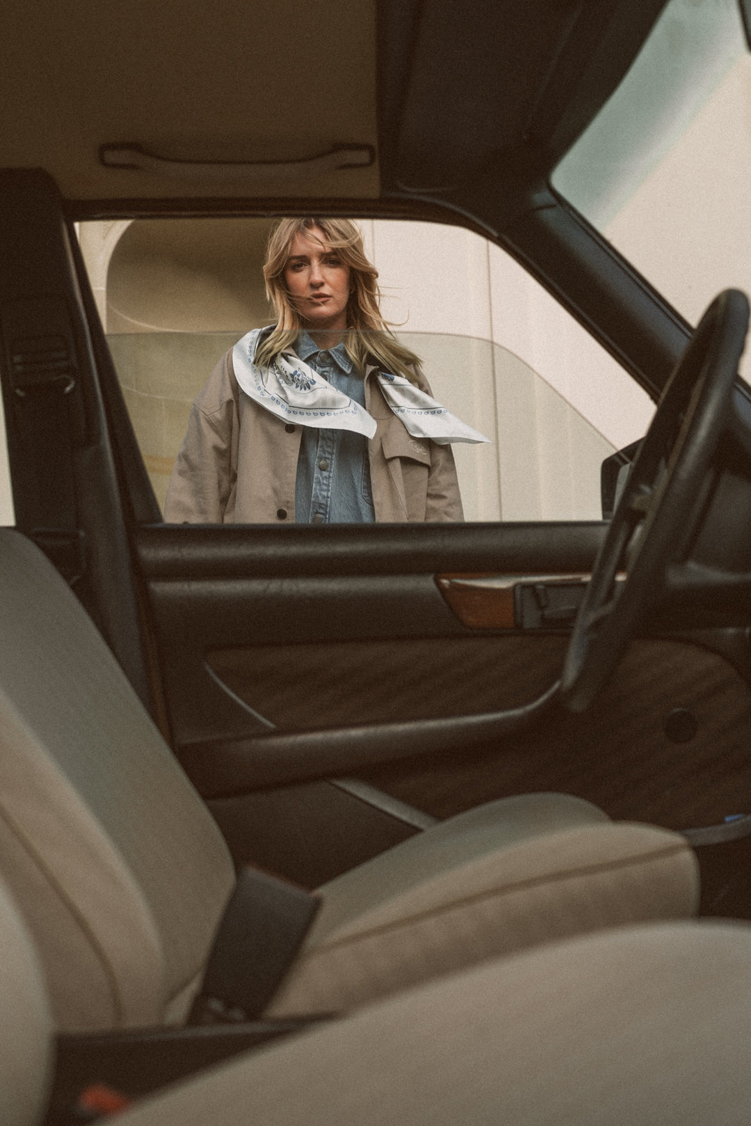 Frau in beiger Jacket Cord Collar mit weißem Silk Scarf, Blick durch Autofenster