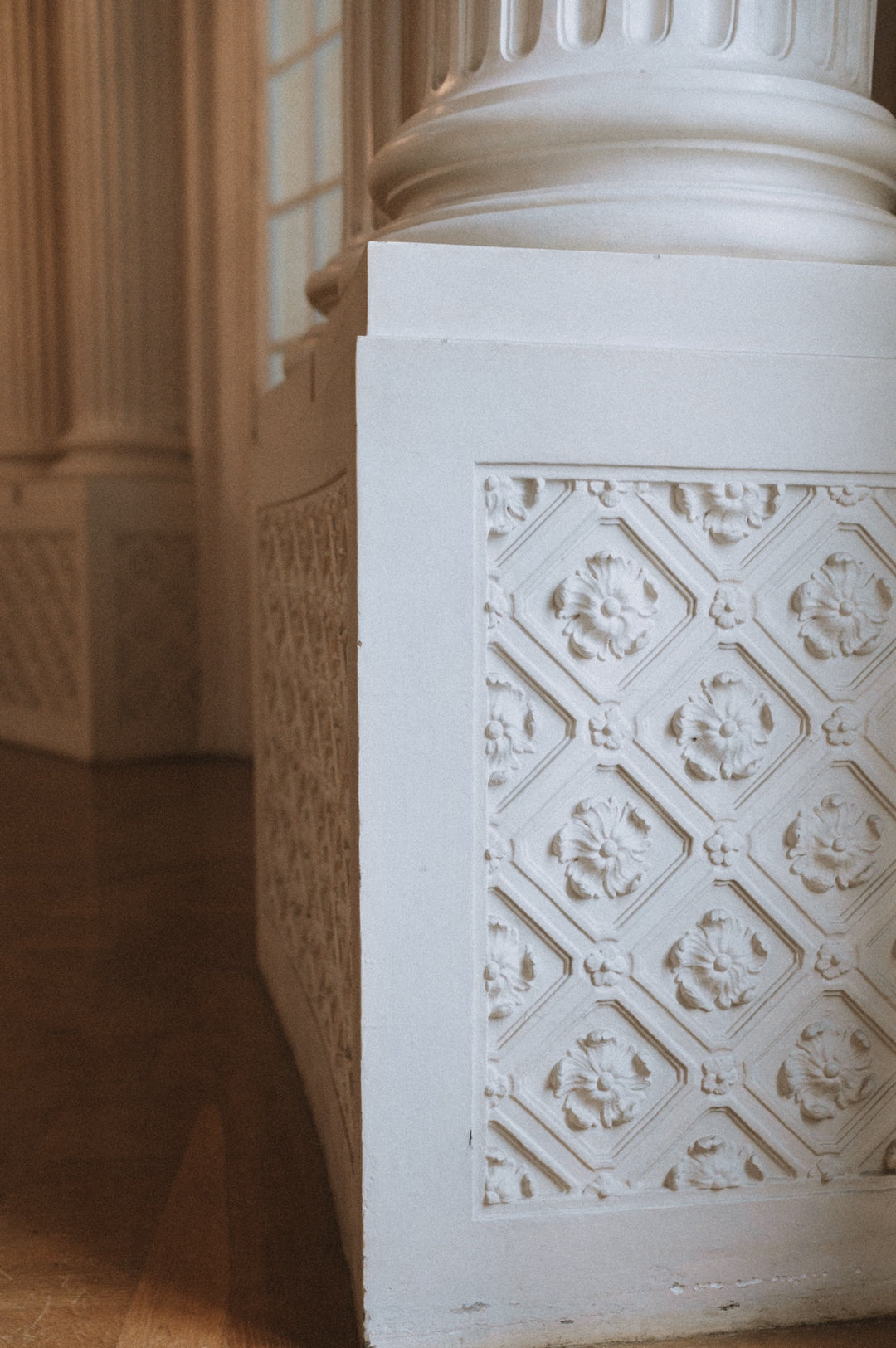 Architekturdetail: Weiße Marmorsäule mit ornamentalen Reliefmustern und Blütenmotiven