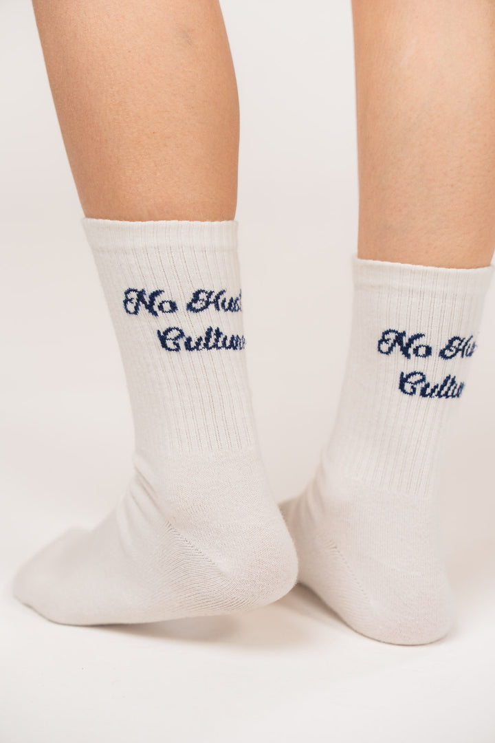 Detailansicht offwhitefarbener Socken aus der No Hustle Culture Kollektion mit blauem Schriftzug „No Hustle Culture“