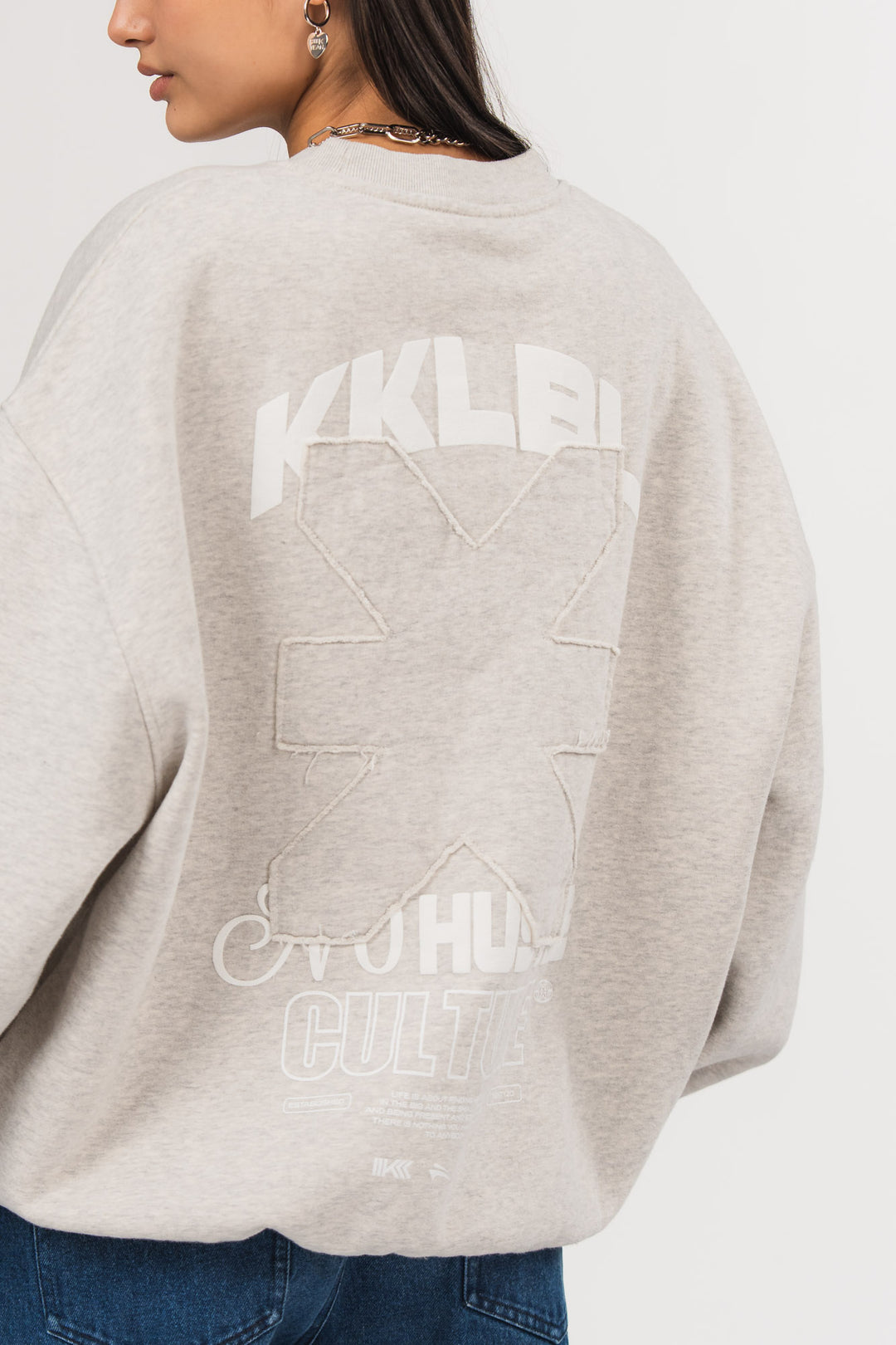 Rückansicht eines hellgrauen Oversize-Sweatshirts aus der No Hustle Culture Kollektion mit großem Rückenprint aus weißem „KKLBL“-Schriftzug, weißem „No Hustle Culture“-Schriftzug und aufgesetztem farbgleichem Logo-Patch in der Mitte