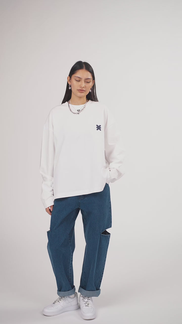 Ein Model in Ganzkörperansicht, das den Look in Bewegung aus verschiedenen Perspektiven zeigt, trägt ein hellgraues Oversize-Sweatshirt mit verschiedenen Prints, kombiniert mit einer blauen Cut-out-Jeans aus der No Hustle Culture Kollektion, weißen Sneakern und silberfarbenem Schmuck