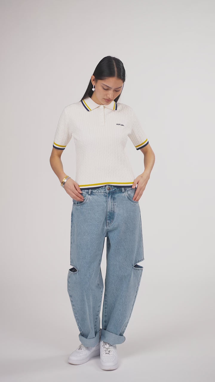 Ein Model in Ganzkörperansicht, das den Look in Bewegung aus verschiedenen Perspektiven zeigt, trägt ein offwhite Strick-Poloshirt und eine hellblaue Cut-out-Jeans aus der No Hustle Culture Kollektion, kombiniert mit weißen Sneakern und silberfarbenem Schmuck